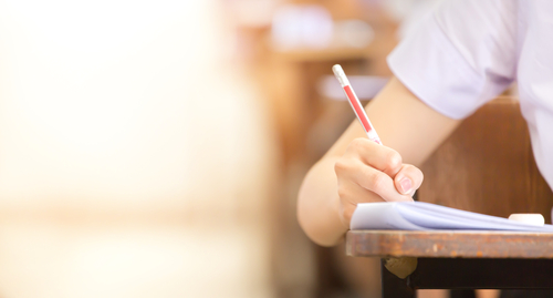 Student holding pencil writing on paper